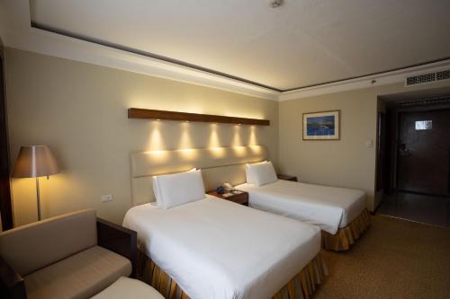 a hotel room with two beds and a chair at Marco Polo Plaza Cebu in Cebu City