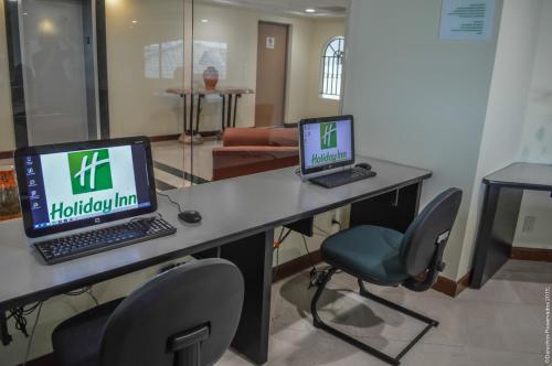two laptop computers sitting on a desk with chairs at Holiday Inn Leon-Convention Center by IHG in León