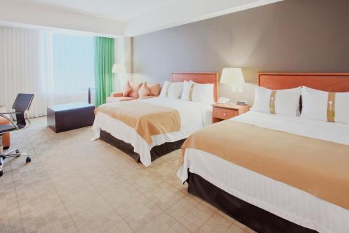 a hotel room with two beds and a chair at Holiday Inn Irapuato by IHG in Irapuato