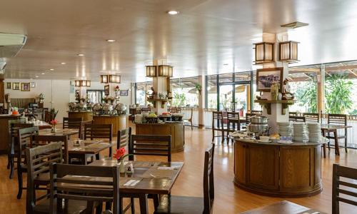 a restaurant with wooden tables and chairs and windows at Phowadol Resort And Spa in Chiang Rai