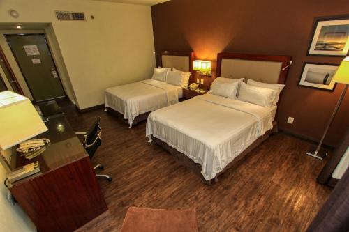 a hotel room with two beds and a desk at Holiday Inn Leon by IHG in León