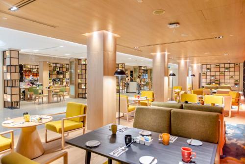 a restaurant with yellow chairs and tables and chairs at Holiday Inn Bangkok by IHG in Bangkok