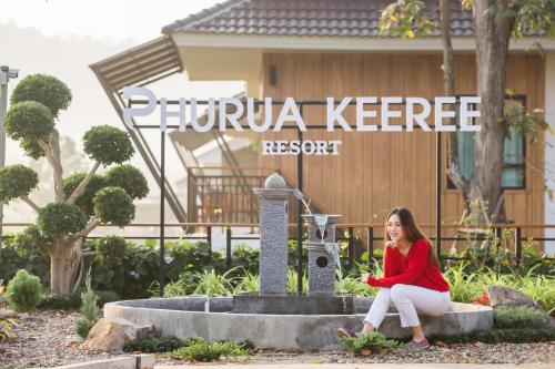 uma mulher sentada numa fonte em frente a uma casa em Phuruakeeree Resort em Loei