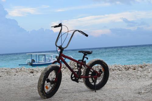 a bike parked on the beach with a boat at Meno Island Villas in Gili Meno