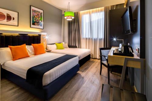 a hotel room with two beds and a desk at Holiday Inn Bologna - Fiera by IHG in Bologna