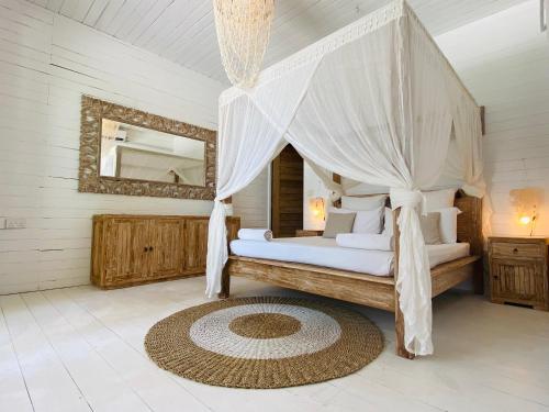 a bedroom with a canopy bed and a mirror at Met House in Thulusdhoo