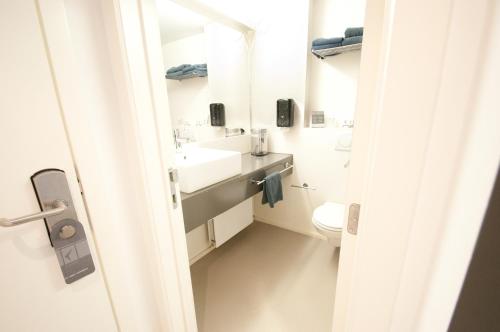 een witte badkamer met een wastafel en een toilet bij Hotel Corbie Geel in Geel