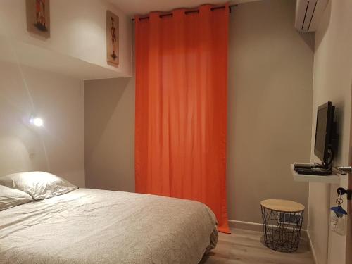 a bedroom with a bed and an orange curtain at Le Saint Jean in Barbentane
