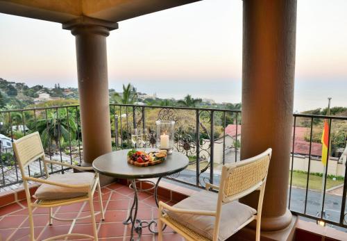 a dining room table with chairs and a balcony at The Vineyard on Ballito in Ballito