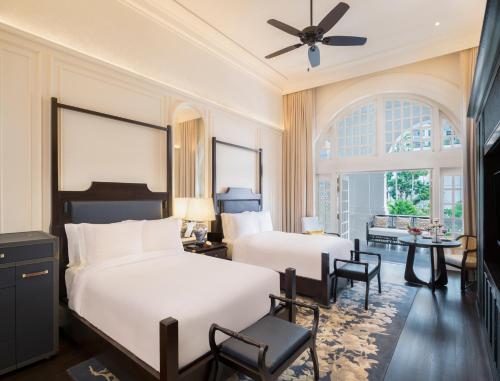 a bedroom with two beds and a table and chairs at Raffles Singapore in Singapore