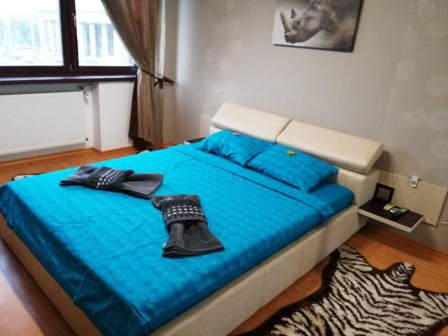 Una cama con sábanas azules y zapatos negros. en CoquetteHouse Parc Gara de Nord, en Bucarest