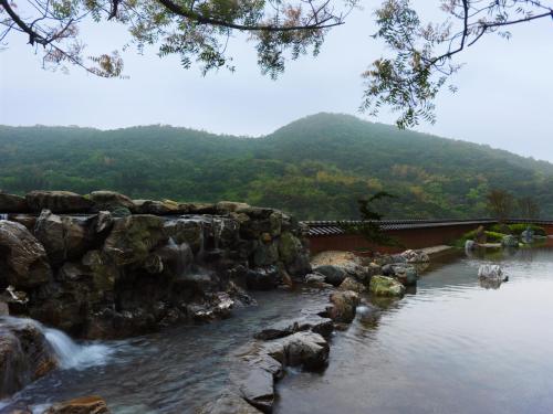 a river with a bridge and a mountain in the background at Yusense Hotel in Taipei