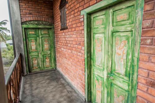 two green doors on the side of a brick building at Negombo Boutique Villa in Negombo