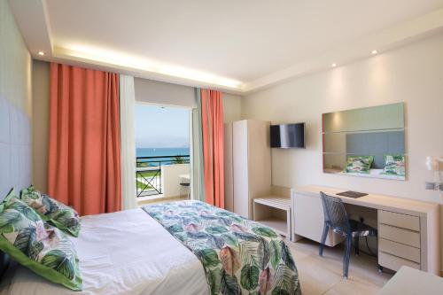 a hotel room with a bed and a desk and a window at Mareblue Beach in Agios Spyridon Corfu