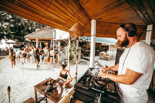 a man wearing headphones standing next to a dj at Tiki Beach Koh Phangan Beach Restaurant Bar and Coworking in Ban Tai