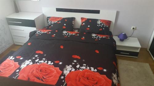 1 Schlafzimmer mit 2 Betten mit schwarzen und roten Blumen in der Unterkunft Alex Deluxe Apartments in Sonnenstrand