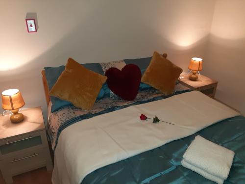 a bed with a heart pillow and a rose on it at Phoenix Nights Guest House in Barrow in Furness