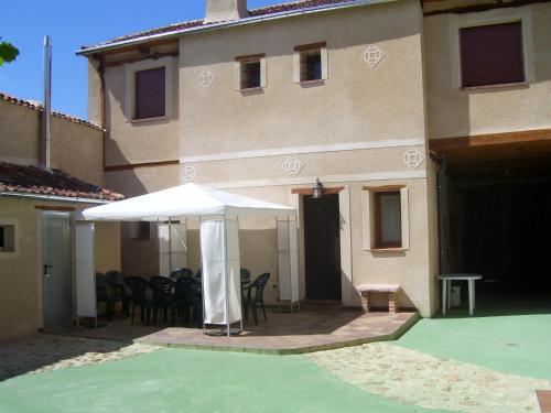 a patio with an umbrella and chairs and a building at Casa Rural la Ribera in Cabezuela