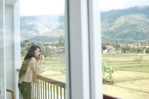 a woman standing in front of a window looking out at Hotel Santika Garut in Garut