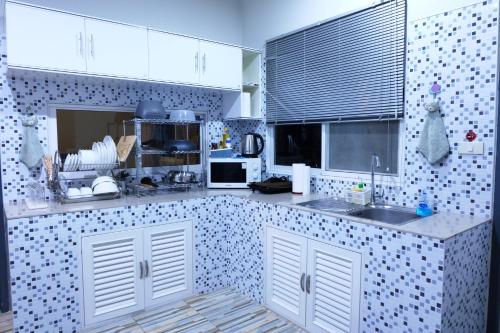 una cocina con armarios blancos y una pared de azulejos en Entire Home 6guests Close city Full Kitchen, en Chiang Mai