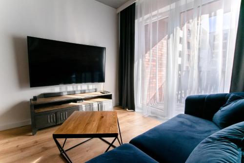 a living room with a blue couch and a flat screen tv at Apartament Małopanewska Wrocław Centrum in Wrocław