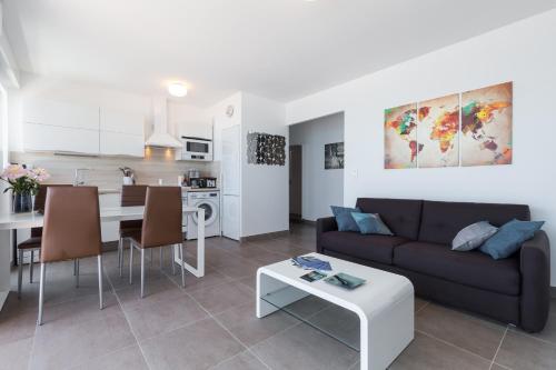 un salon et une cuisine avec un canapé et une table dans l'établissement GORGEOUS APT with TERRACE, ELEVATOR, AC, FREE PARKING - Le Régis, à Cagnes-sur-Mer