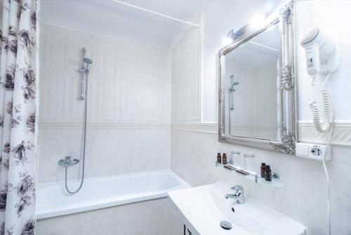 a white bathroom with a shower and a sink at Forums Boutique Hotel in Rīga