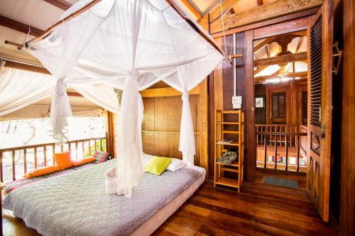 a bedroom with a canopy bed in a house at Cat Tien Farm Stay in Tân Phú
