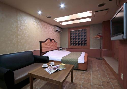 a hotel room with a bed and a couch and a table at Hotel Mio Resort ( Adult Only) in Yokkaichi