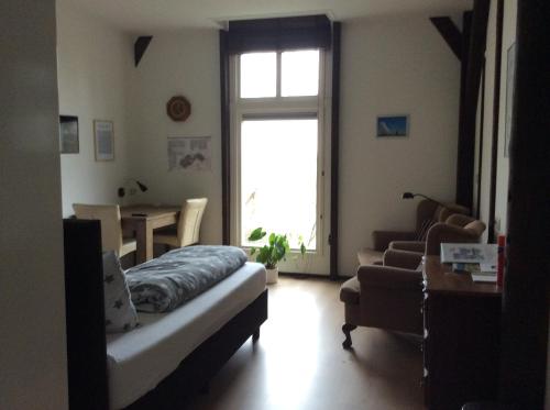 ein Wohnzimmer mit einem Bett, einem Tisch und einem Fenster in der Unterkunft B & B Zazza in Rauwerd