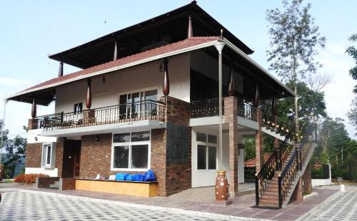 a house with a balcony on the side of it at Lake Trail Homestay Coorg in Madikeri