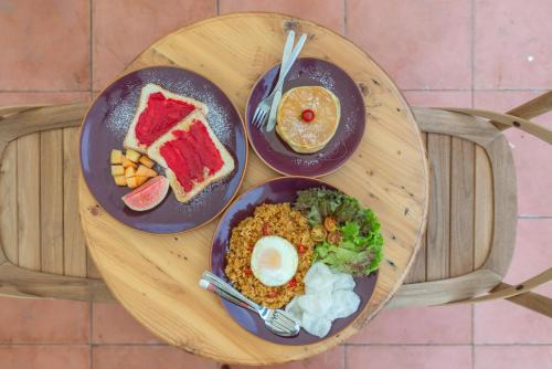 a wooden table with two plates of food on it at Wonderloft Hostel Jogja in Yogyakarta