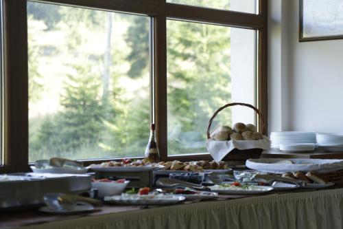 a table with plates of food in front of a window at Hotel Coop Rozhen in Pamporovo