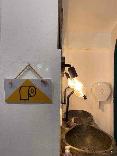 a bathroom with a sink and a light on a wall at Wonderloft Hostel Jogja in Yogyakarta