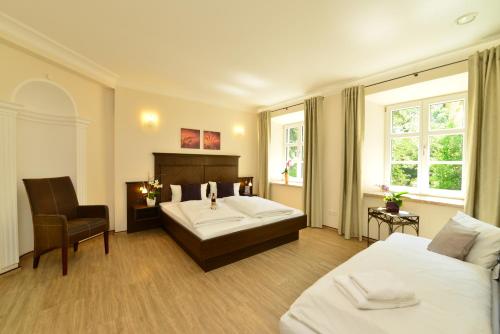 a hotel room with two beds and a chair at Autenrieder Brauereigasthof in Ichenhausen
