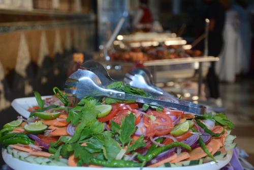 a plate of salad with tongs and vegetables on it at Urban Rose Hotel & Apartments in Dar es Salaam