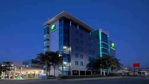 a building with a green sign on the side of it at Holiday Inn Irapuato by IHG in Irapuato