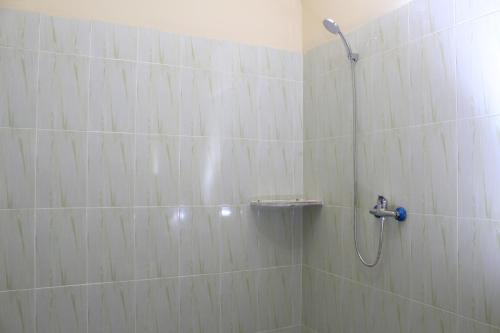 a shower in a bathroom with white tile at Teman Teman Bungalows 1 in Amed
