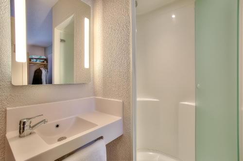 a bathroom with a sink and a mirror at B&B HOTEL Antibes Sophia Antipolis in Biot