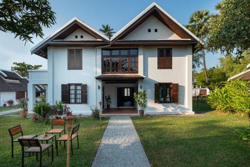 a house with a table and chairs in the yard at Sanctuary Hotel Luang Prabang in Luang Prabang