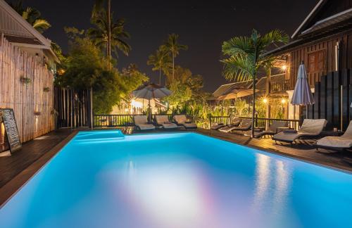 a pool at night with chairs and umbrellas at Sanctuary Hotel Luang Prabang in Luang Prabang