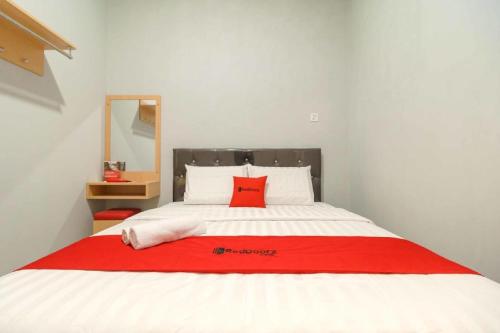 a bed with a red pillow on top of it at RedDoorz @ Helvetia Medan 2 in Pulauberayan