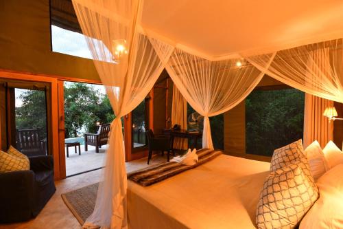 een slaapkamer met een bed met gordijnen en een patio bij Royal Zambezi Lodge in Mafuta