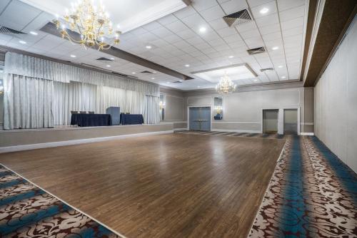 a large ballroom with a wooden floor and a chandelier at enVision Hotel & Conference Center Mansfield-Foxboro in Mansfield