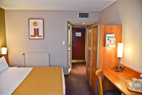 a hotel room with a bed and a wooden desk at Holiday Inn Calais-Centre by IHG in Calais