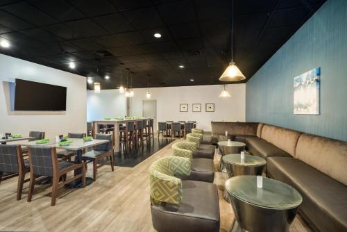 a restaurant with couches and tables and a flat screen tv at enVision Hotel & Conference Center Mansfield-Foxboro in Mansfield