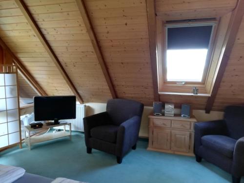 ein Wohnzimmer mit 2 Stühlen und einem TV in der Unterkunft Haus Timmerloher Forst in Schneverdingen