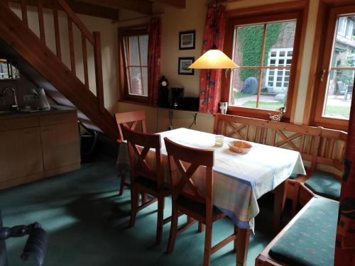 eine Küche mit einem Tisch mit Stühlen und einem weißen Tischtuch in der Unterkunft Haus Timmerloher Forst in Schneverdingen