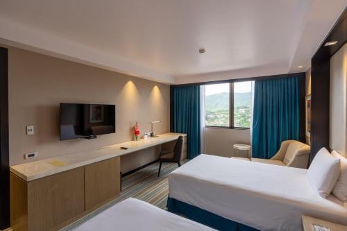 a hotel room with two beds and a desk and a tv at Marco Polo Plaza Cebu in Cebu City