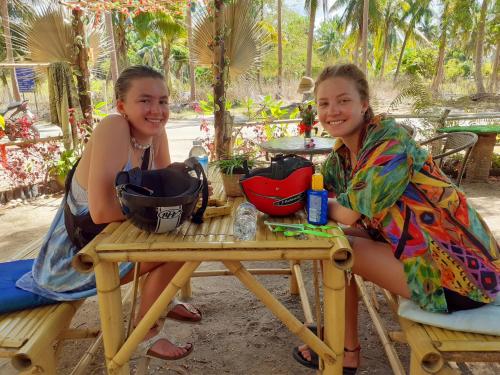 Dos chicas están sentadas en una mesa de picnic. en Bamboo Bungalow Baan Tai Phangan, en Baan Tai